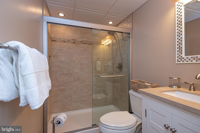 bathroom featuring vanity, a shower with door, and toilet