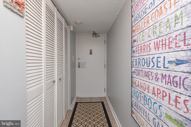 hallway featuring tile patterned floors and a textured ceiling