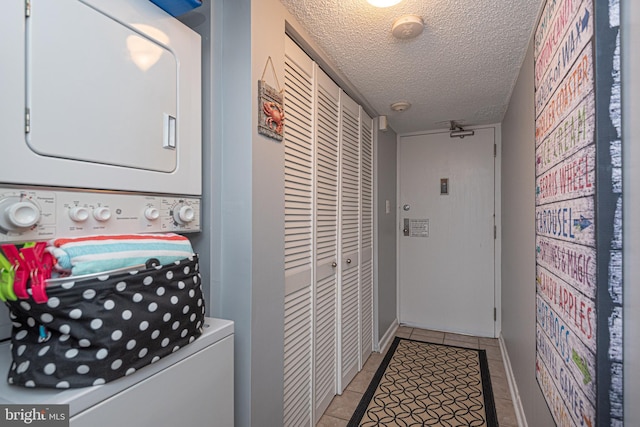 laundry area featuring stacked washer and clothes dryer, a textured ceiling, and light tile patterned floors