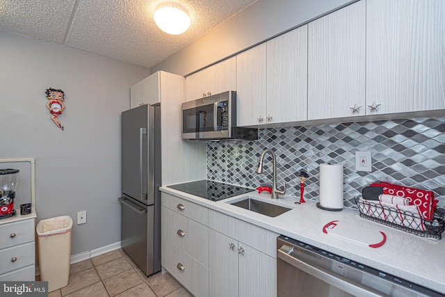 kitchen with sink, stainless steel appliances, tasteful backsplash, a textured ceiling, and light tile patterned flooring