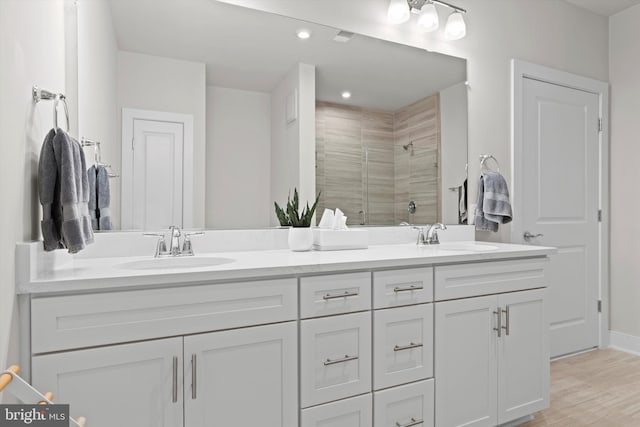 bathroom with hardwood / wood-style flooring, vanity, and walk in shower