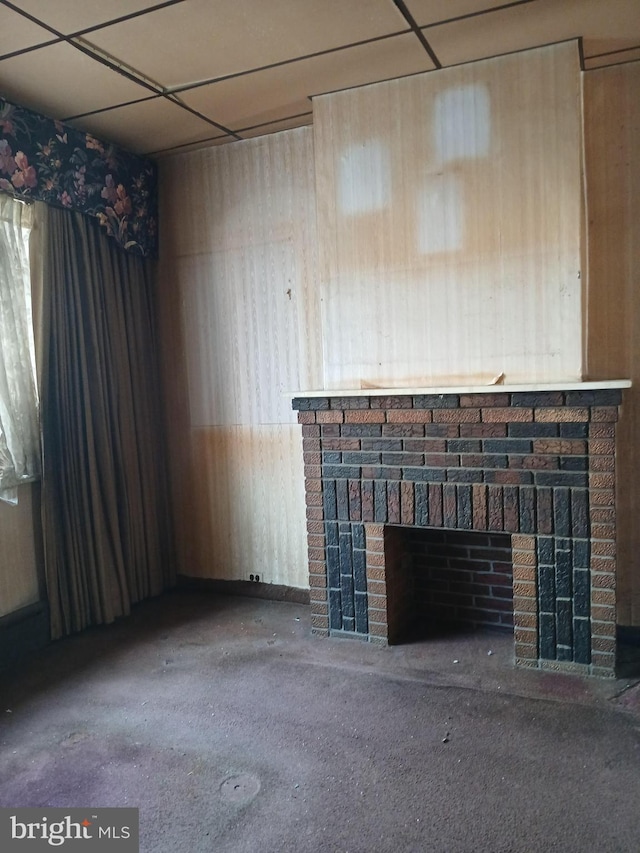 unfurnished living room featuring a brick fireplace and wooden walls