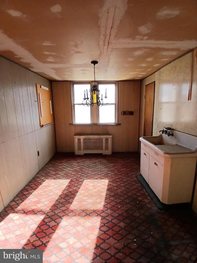 interior space featuring radiator heating unit, a notable chandelier, and wooden walls