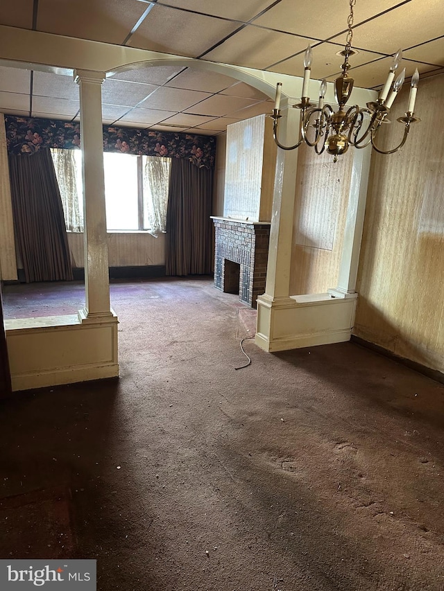 interior space with a fireplace, decorative columns, carpet, and a drop ceiling