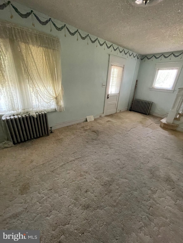 spare room with radiator, a textured ceiling, and carpet flooring