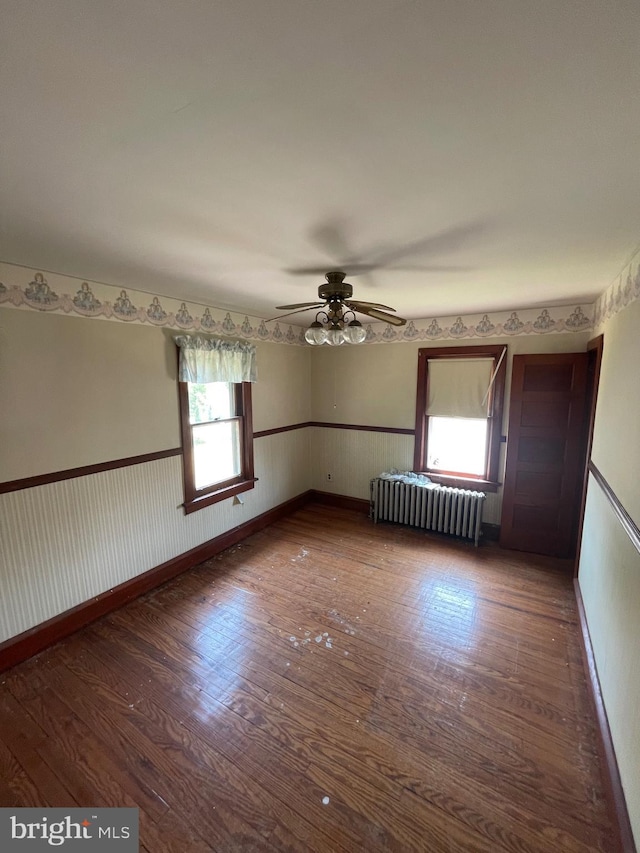 spare room with ceiling fan, dark hardwood / wood-style floors, and radiator