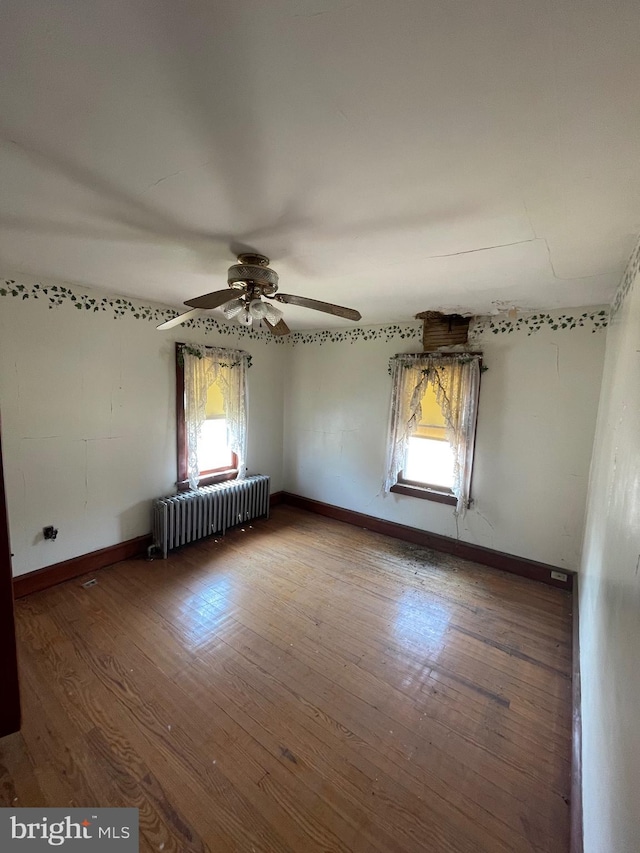 spare room with ceiling fan, radiator heating unit, and hardwood / wood-style floors