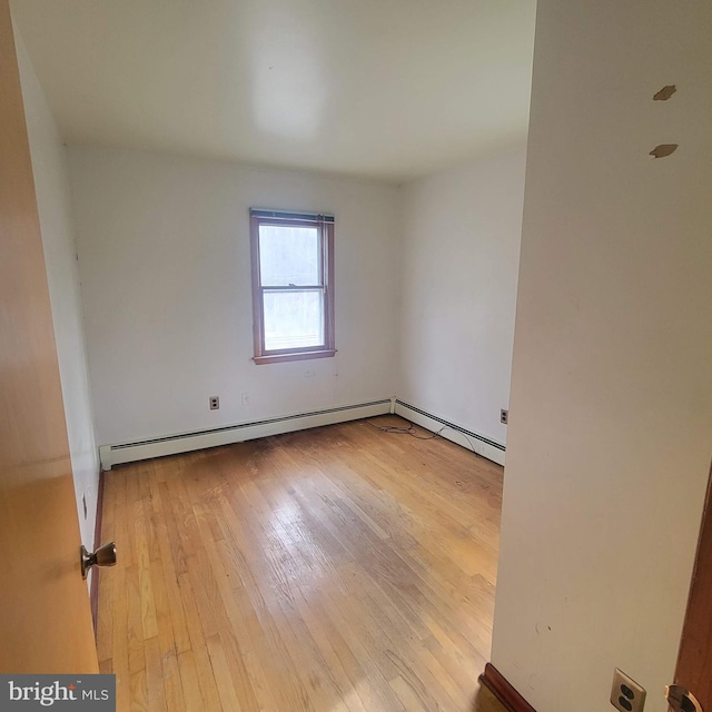 empty room with light wood-style floors and a baseboard radiator