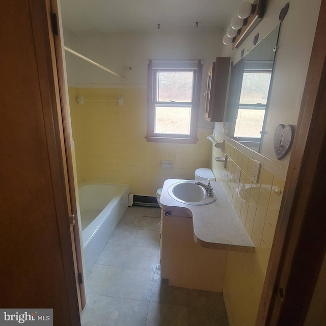 full bath with toilet, tile patterned floors, tile walls, and vanity