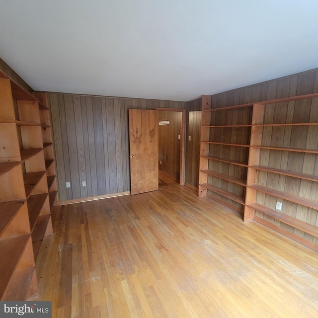 empty room featuring light wood finished floors and wood walls