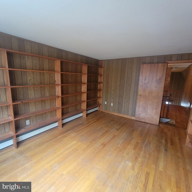 empty room with light wood finished floors and wood walls