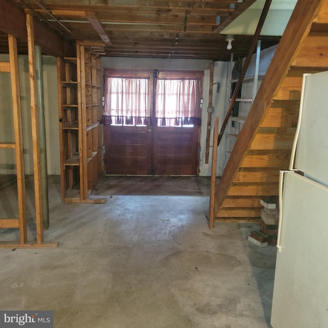 basement with freestanding refrigerator and stairway