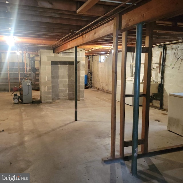 unfinished below grade area featuring washer / clothes dryer, a heating unit, and a sink