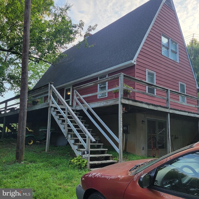 back of house featuring roof with shingles and stairs