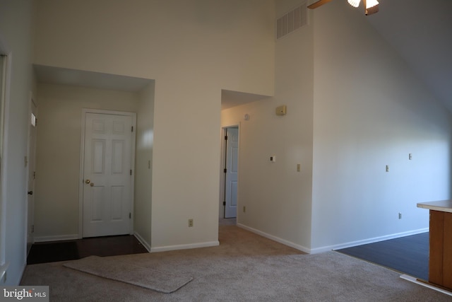 carpeted spare room featuring ceiling fan and a high ceiling