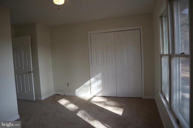 unfurnished bedroom with ceiling fan, carpet flooring, and a closet