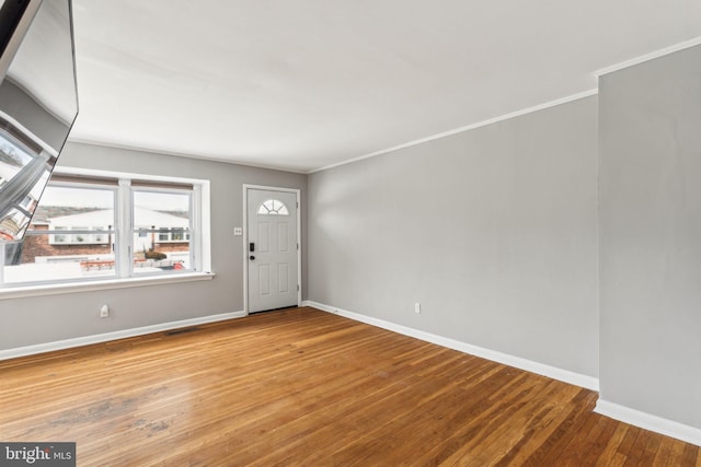 entryway featuring baseboards, wood finished floors, and crown molding