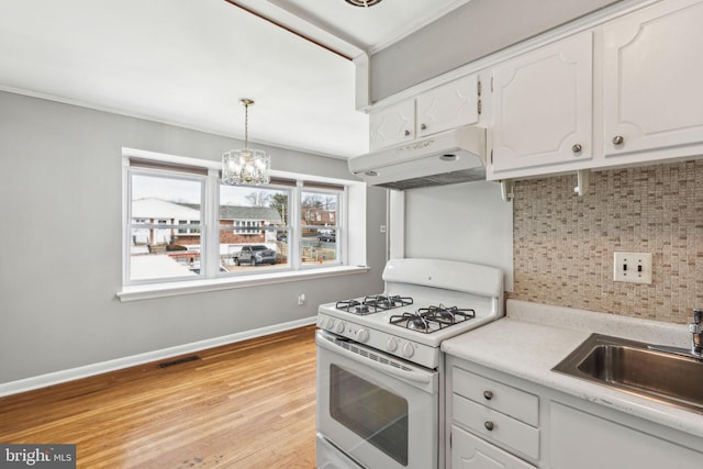 kitchen with gas range gas stove, pendant lighting, light countertops, under cabinet range hood, and white cabinets