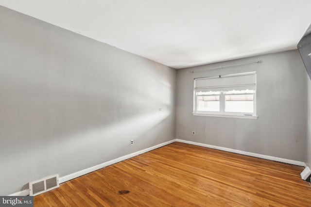 empty room featuring baseboards, visible vents, and wood finished floors