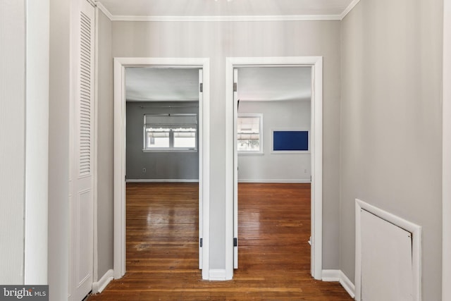 hall featuring dark wood finished floors, baseboards, and ornamental molding