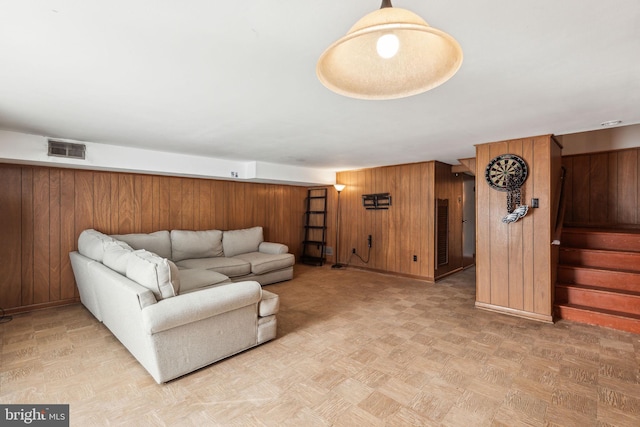 living area with stairs, visible vents, and wooden walls