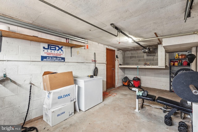 basement with concrete block wall and fridge