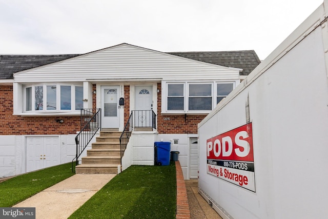 view of front of house with brick siding and roof with shingles