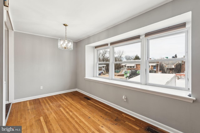 unfurnished room with baseboards, visible vents, crown molding, a notable chandelier, and wood finished floors