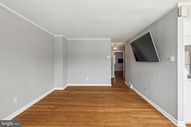 unfurnished room featuring ornamental molding, baseboards, and wood finished floors