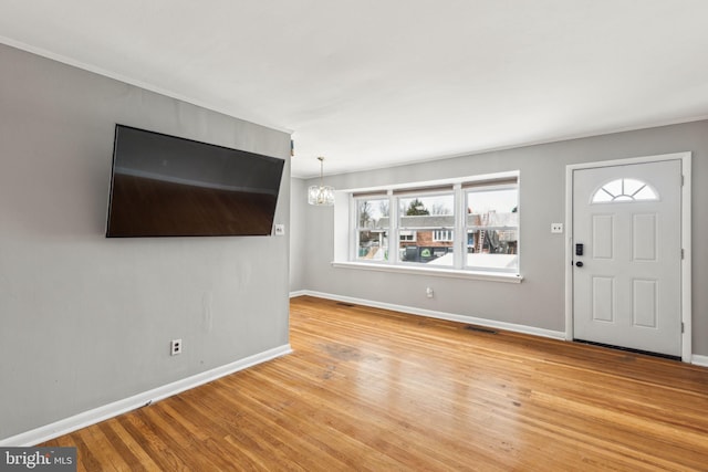 entrance foyer featuring light wood-style floors, visible vents, baseboards, and an inviting chandelier