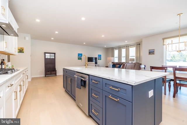 kitchen with sink, appliances with stainless steel finishes, hanging light fixtures, white cabinets, and a center island with sink