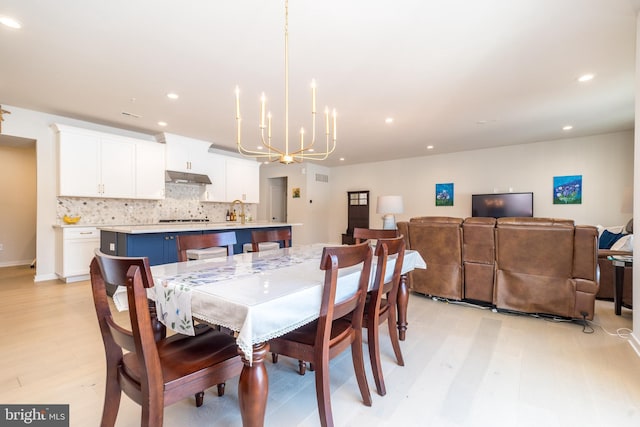 dining room featuring an inviting chandelier, sink, and light hardwood / wood-style flooring