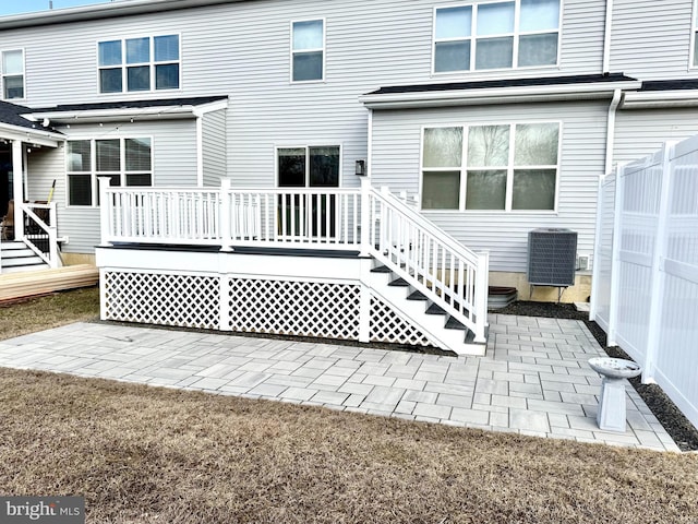 rear view of property featuring cooling unit, a wooden deck, and a patio