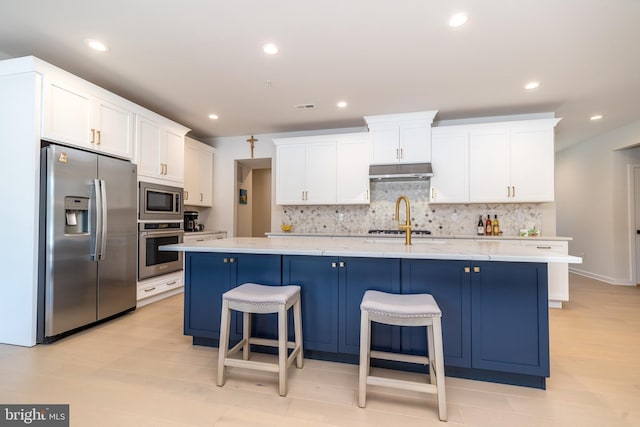 kitchen featuring white cabinetry, appliances with stainless steel finishes, a breakfast bar, and an island with sink