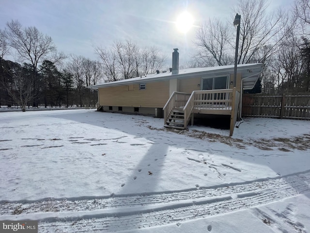 snow covered rear of property featuring a deck