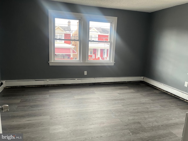 spare room with wood-type flooring, a textured ceiling, and baseboard heating