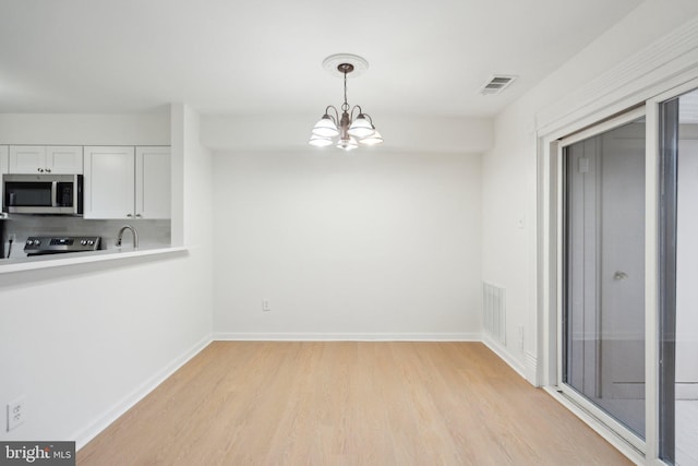 unfurnished dining area featuring sink, light hardwood / wood-style flooring, and a chandelier