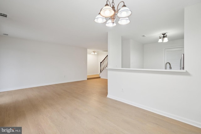 spare room with sink, a notable chandelier, and light hardwood / wood-style floors