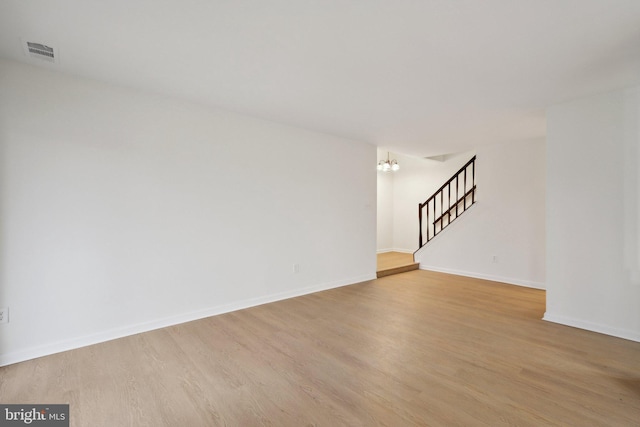 empty room featuring light hardwood / wood-style flooring and a notable chandelier