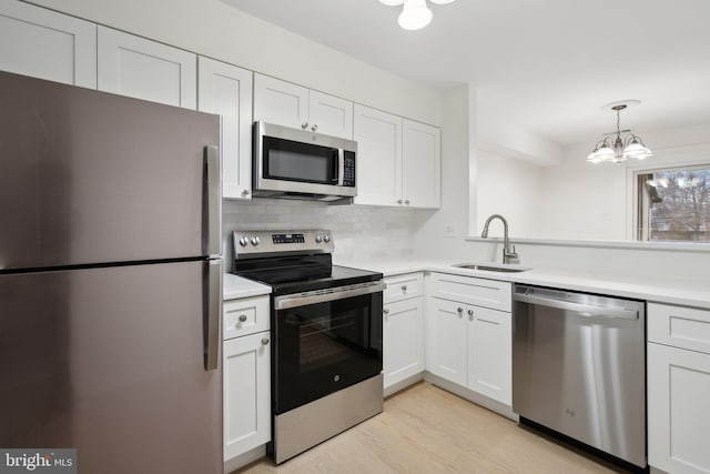 kitchen with pendant lighting, sink, white cabinets, and appliances with stainless steel finishes