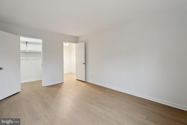 unfurnished bedroom featuring a spacious closet, light hardwood / wood-style floors, and a closet