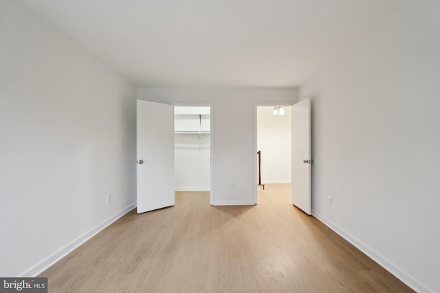 unfurnished bedroom featuring a spacious closet, light hardwood / wood-style floors, and a closet