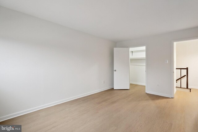 unfurnished bedroom featuring a walk in closet, light hardwood / wood-style flooring, and a closet