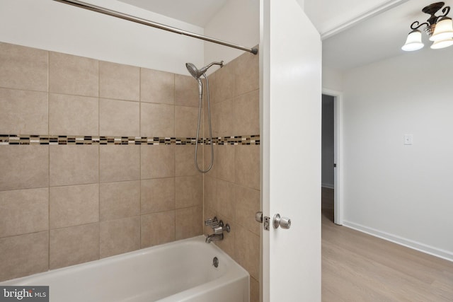 bathroom featuring wood-type flooring and tiled shower / bath