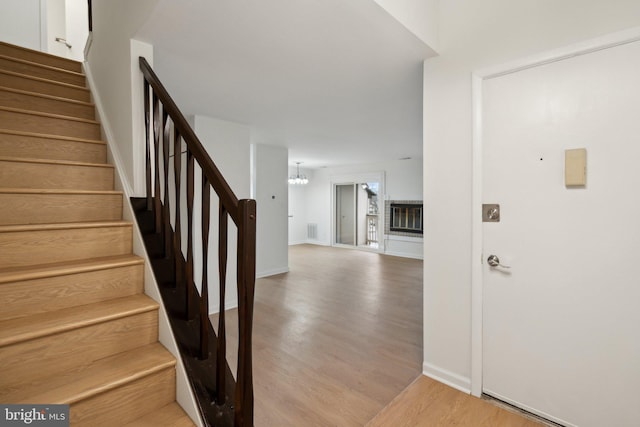 stairs featuring hardwood / wood-style floors and a chandelier