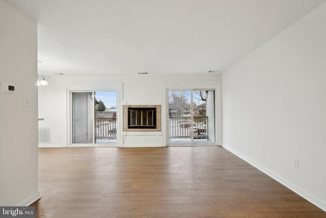 unfurnished living room featuring a fireplace, hardwood / wood-style flooring, and plenty of natural light