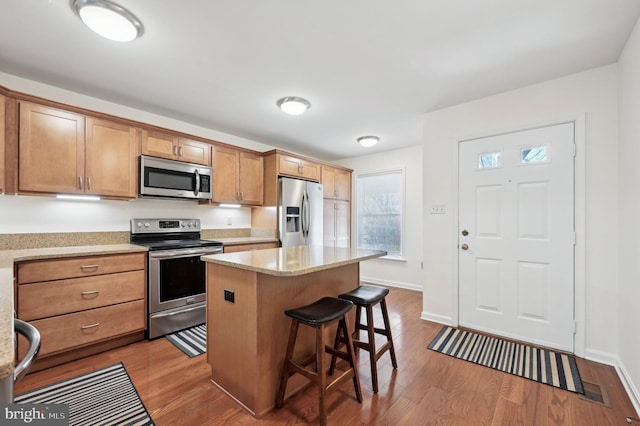 kitchen featuring appliances with stainless steel finishes, a kitchen breakfast bar, light hardwood / wood-style floors, and a kitchen island