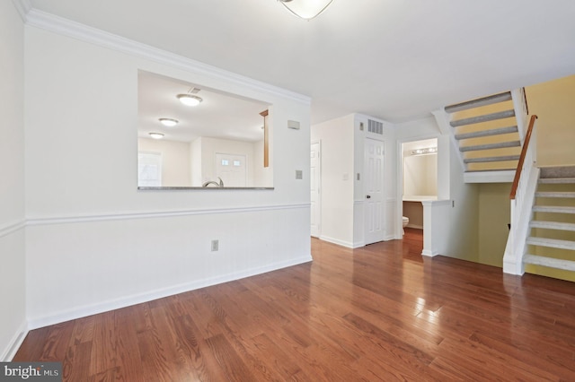 unfurnished living room featuring wood-type flooring and ornamental molding