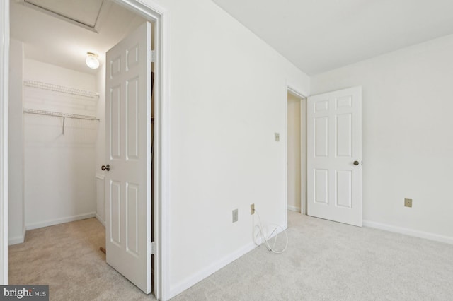 unfurnished bedroom featuring light colored carpet, a spacious closet, and a closet