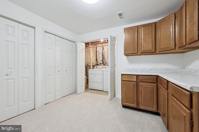 kitchen featuring light colored carpet and washing machine and dryer